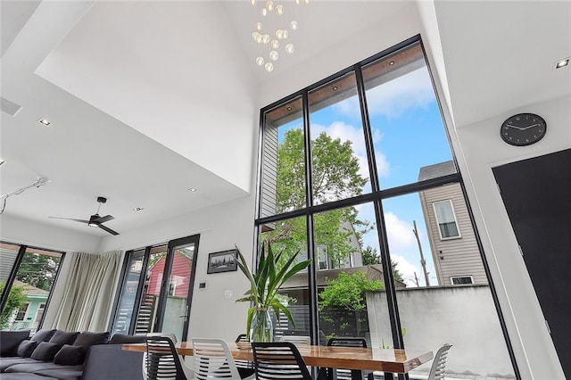 interior space featuring a high ceiling, ceiling fan with notable chandelier, and a wealth of natural light