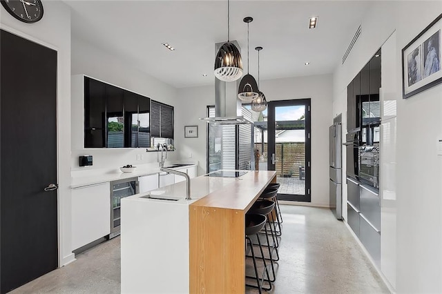 kitchen featuring a center island, wine cooler, hanging light fixtures, black electric stovetop, and high quality fridge