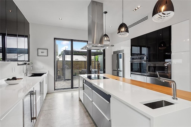 kitchen with hanging light fixtures, sink, stainless steel appliances, and island range hood