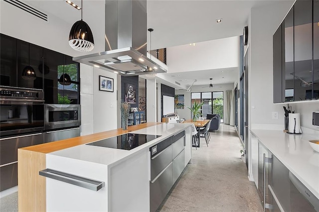 kitchen with decorative light fixtures, a kitchen island, ceiling fan, island range hood, and black appliances