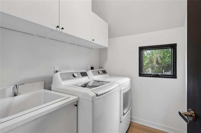 washroom with light wood-type flooring, electric dryer hookup, independent washer and dryer, sink, and cabinets