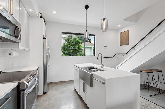 kitchen with pendant lighting, appliances with stainless steel finishes, white cabinets, and sink