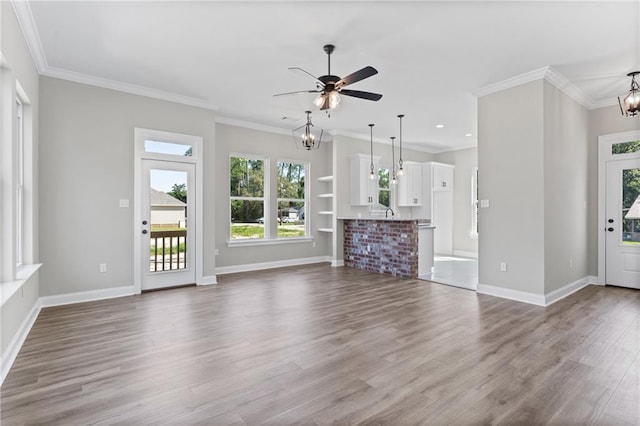 unfurnished living room featuring wood-type flooring, ceiling fan with notable chandelier, and crown molding