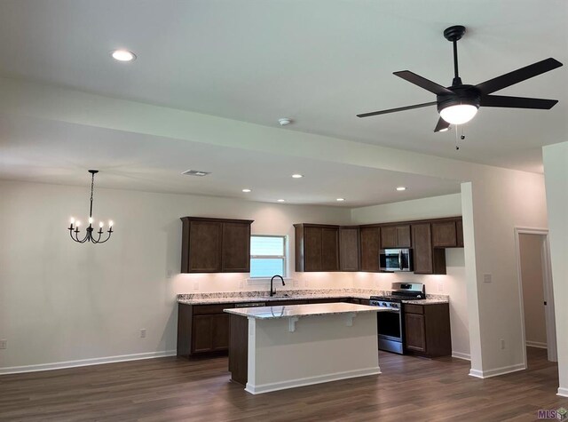 kitchen featuring stainless steel appliances, dark hardwood / wood-style flooring, ceiling fan with notable chandelier, sink, and a center island