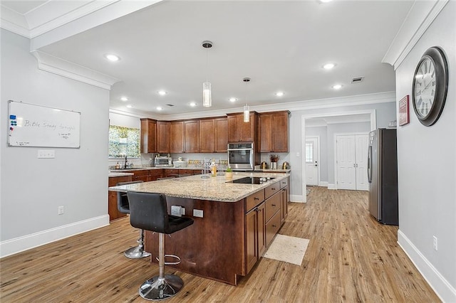 kitchen with a center island, crown molding, light hardwood / wood-style flooring, appliances with stainless steel finishes, and pendant lighting