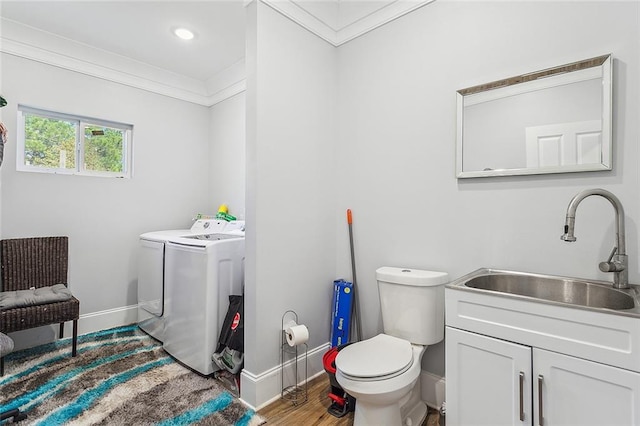 bathroom with hardwood / wood-style flooring, toilet, crown molding, washer and dryer, and sink