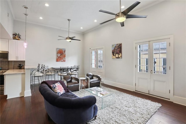 living room with a high ceiling, ornamental molding, ceiling fan, and dark hardwood / wood-style floors