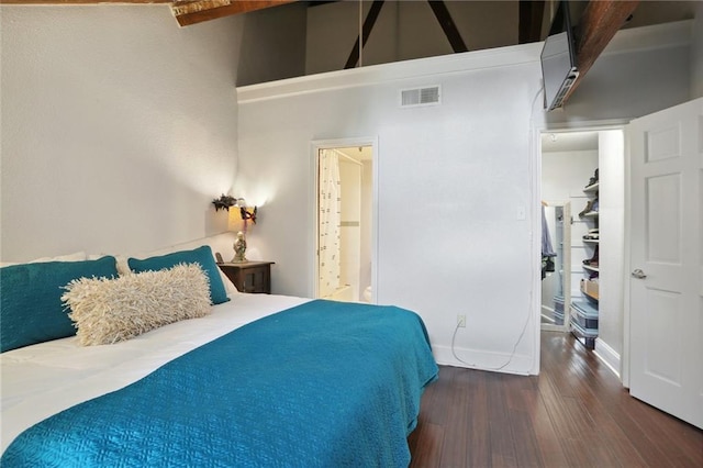 bedroom featuring a towering ceiling, beam ceiling, and dark hardwood / wood-style floors