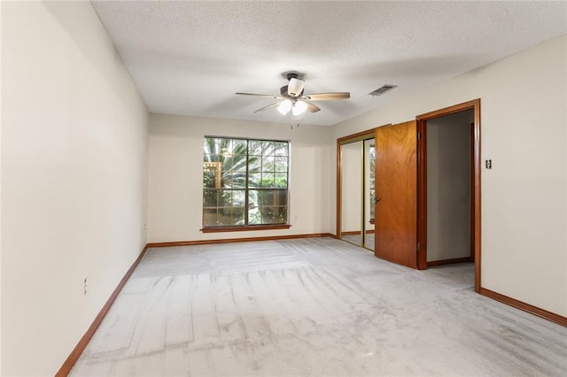 unfurnished bedroom featuring light carpet, a textured ceiling, and ceiling fan