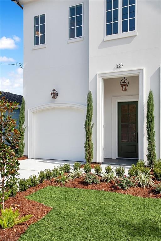 doorway to property with a garage and a lawn