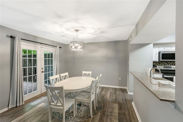 dining space featuring french doors, dark hardwood / wood-style flooring, a notable chandelier, and sink