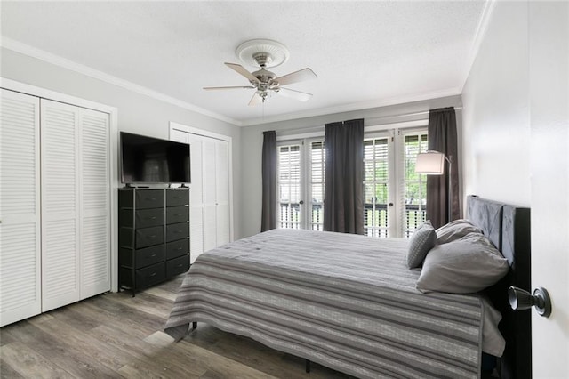 bedroom with multiple closets, ceiling fan, crown molding, and wood-type flooring