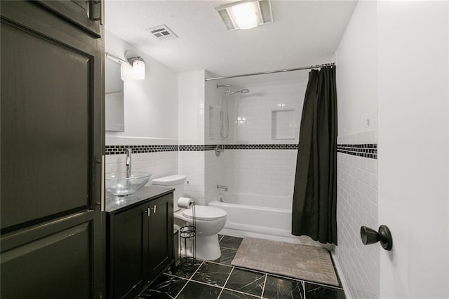 full bathroom with vanity, shower / bath combo, tile walls, and toilet