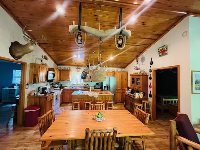 dining room featuring wooden ceiling, light hardwood / wood-style flooring, and vaulted ceiling