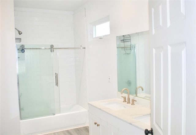 bathroom featuring shower / bath combination with glass door, wood-type flooring, and vanity with extensive cabinet space