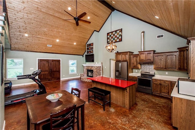 kitchen featuring a fireplace, a healthy amount of sunlight, backsplash, stainless steel appliances, and high vaulted ceiling