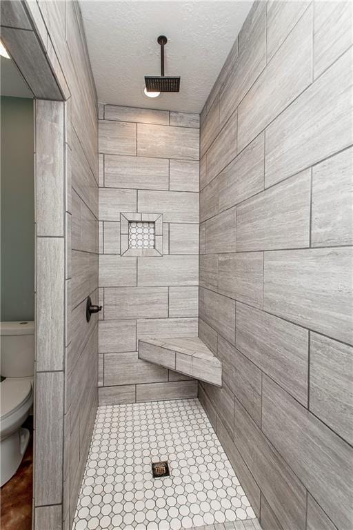 bathroom with a tile shower and toilet