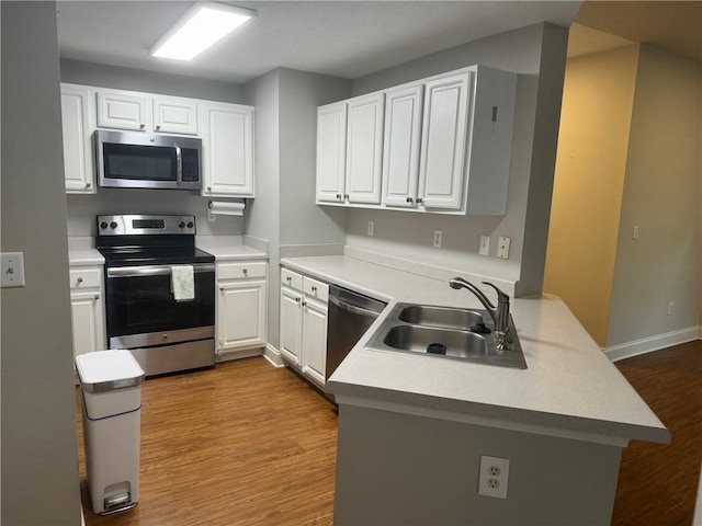 kitchen with white cabinetry, appliances with stainless steel finishes, sink, and kitchen peninsula