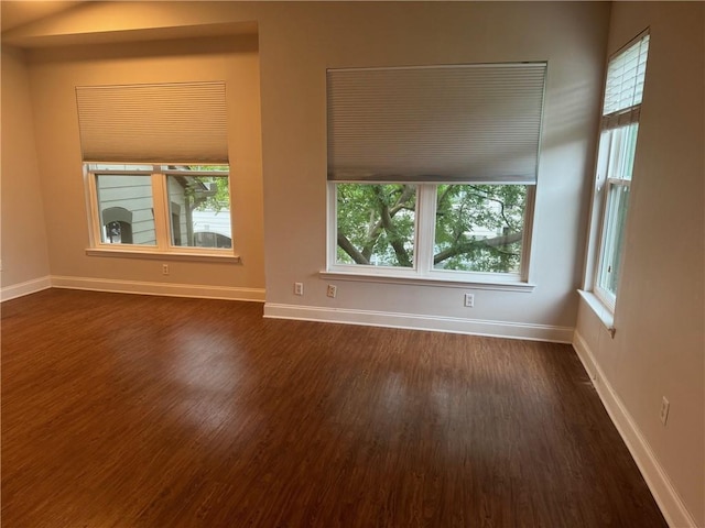 empty room featuring a wealth of natural light and dark wood-type flooring