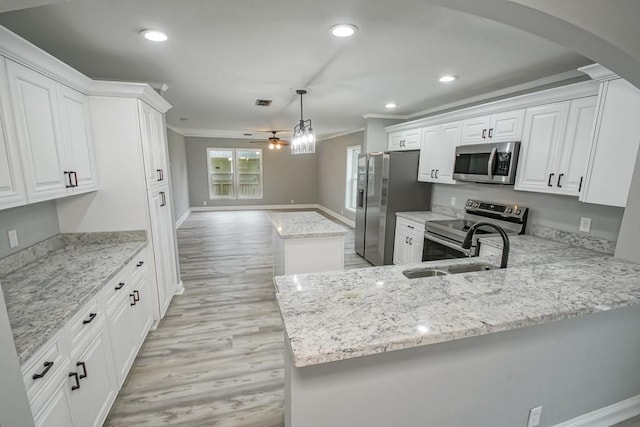 kitchen with ceiling fan, stainless steel appliances, decorative light fixtures, light wood-type flooring, and a kitchen island