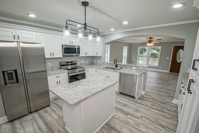 kitchen featuring a kitchen island, stainless steel appliances, ceiling fan, light wood-type flooring, and sink