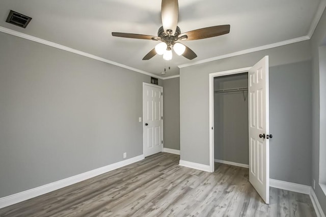 unfurnished bedroom featuring ceiling fan, a closet, ornamental molding, and wood-type flooring