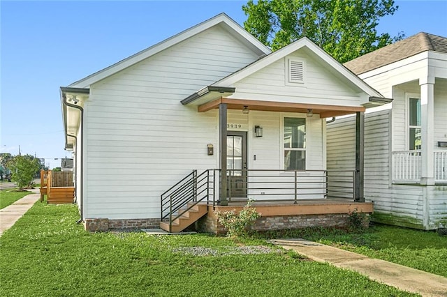 back of property with covered porch and a yard