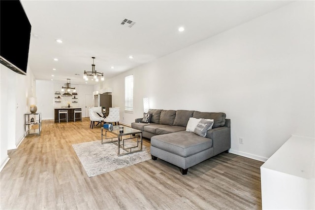 living room featuring a chandelier and light wood-type flooring