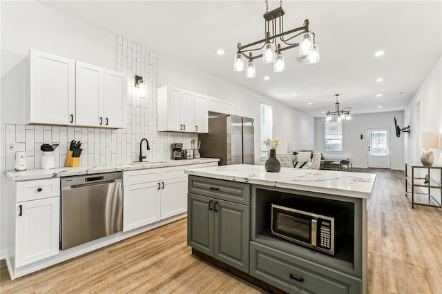 kitchen featuring white cabinets, decorative light fixtures, and appliances with stainless steel finishes