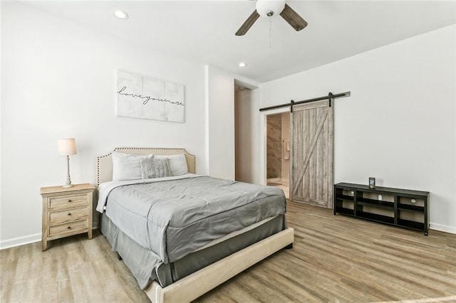 bedroom featuring a barn door, ceiling fan, and wood-type flooring