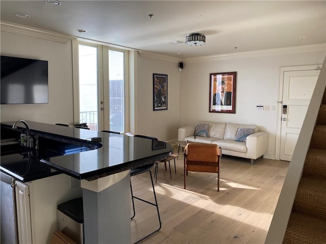 interior space with a breakfast bar area, french doors, kitchen peninsula, light wood-type flooring, and ornamental molding