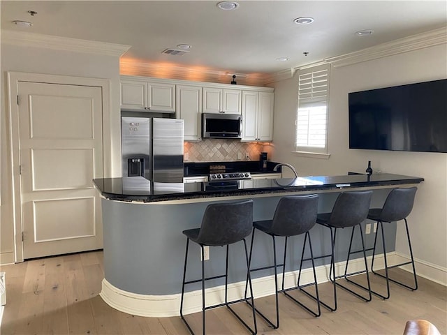 kitchen featuring decorative backsplash, stainless steel appliances, light hardwood / wood-style flooring, and kitchen peninsula