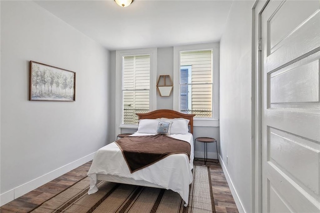 bedroom with dark hardwood / wood-style floors and multiple windows