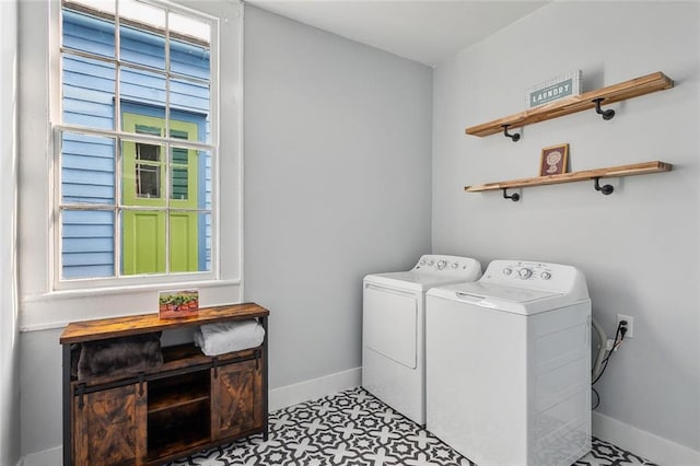 laundry area with a wealth of natural light, washer and clothes dryer, and light tile flooring