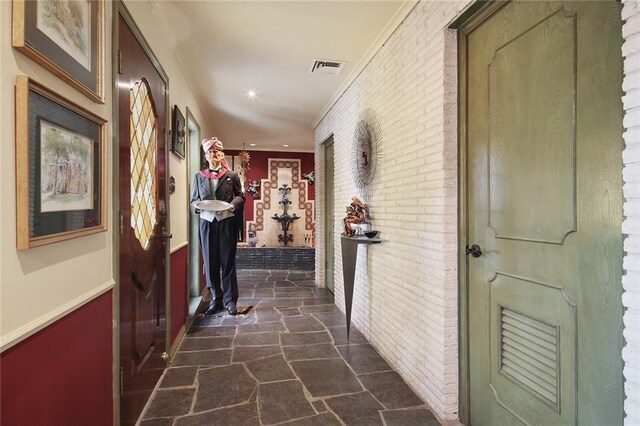 hallway featuring crown molding and brick wall