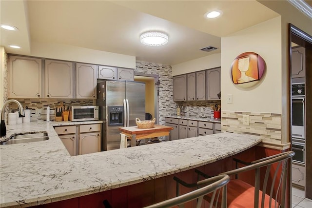 kitchen with oven, sink, stainless steel fridge with ice dispenser, kitchen peninsula, and a breakfast bar area