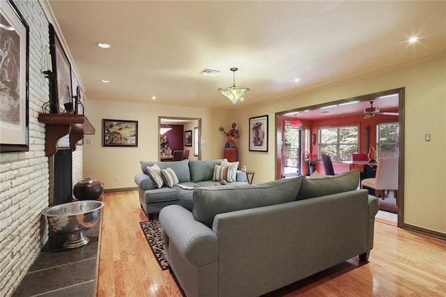 living room with a fireplace, light hardwood / wood-style floors, and ceiling fan