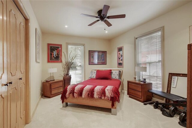 bedroom featuring multiple windows, a closet, light colored carpet, and ceiling fan