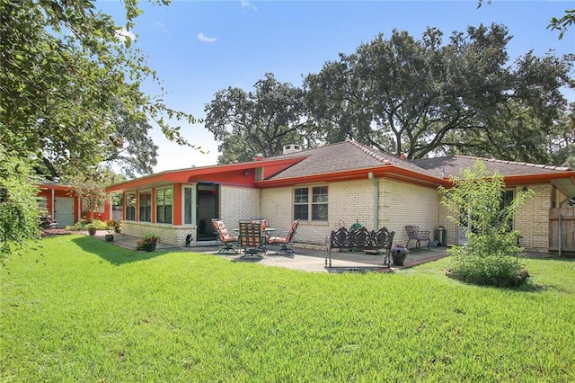 back of property featuring a lawn, a sunroom, and a patio area