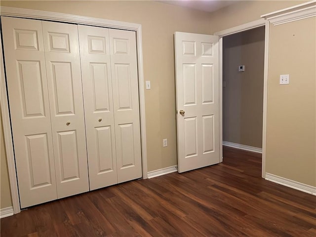 unfurnished bedroom with dark hardwood / wood-style floors and a closet