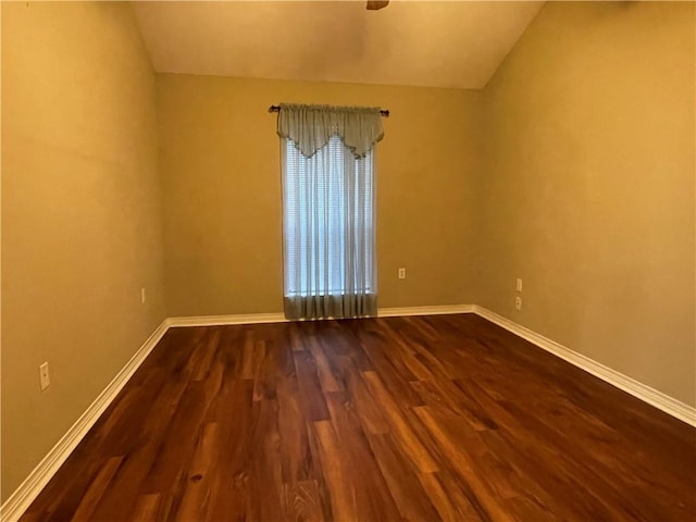 empty room with vaulted ceiling and hardwood / wood-style flooring