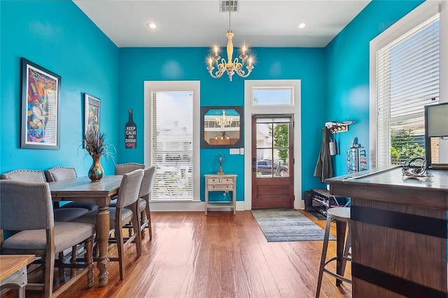 dining room with an inviting chandelier, wood-type flooring, and a healthy amount of sunlight