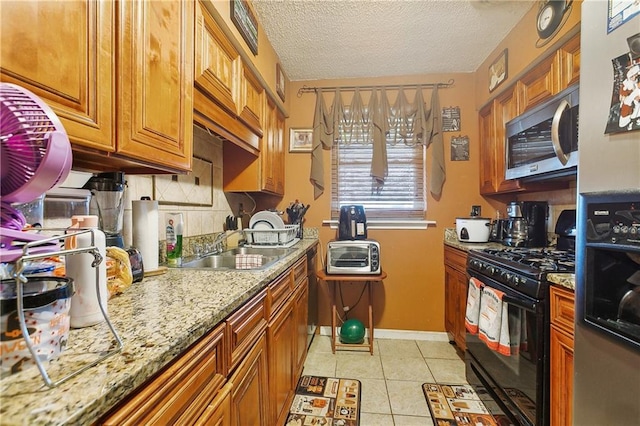 kitchen with light stone countertops, gas stove, a textured ceiling, tasteful backsplash, and light tile floors