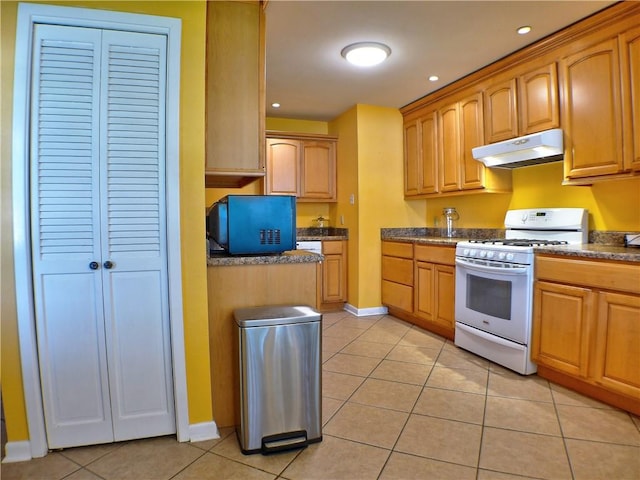 kitchen featuring white range with gas stovetop and light tile patterned flooring