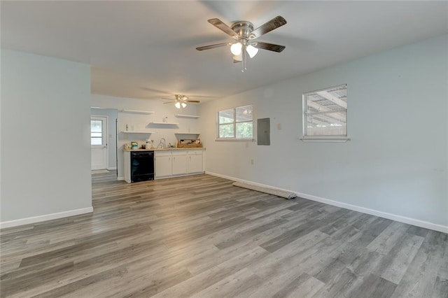 unfurnished living room featuring wine cooler, ceiling fan, hardwood / wood-style floors, and sink