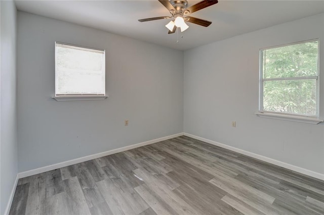 empty room featuring wood-type flooring, plenty of natural light, and ceiling fan