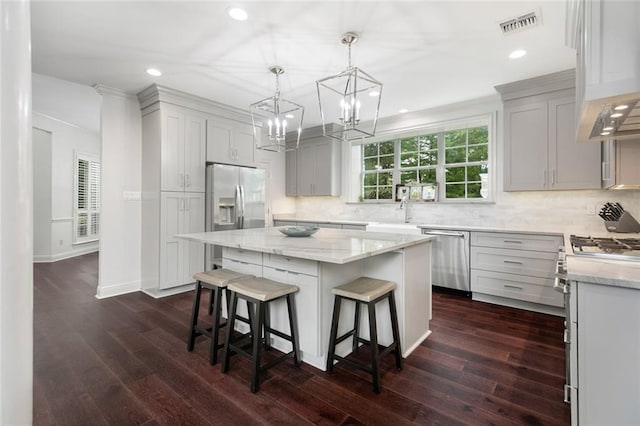 kitchen featuring dark hardwood / wood-style floors, tasteful backsplash, pendant lighting, a kitchen island, and appliances with stainless steel finishes