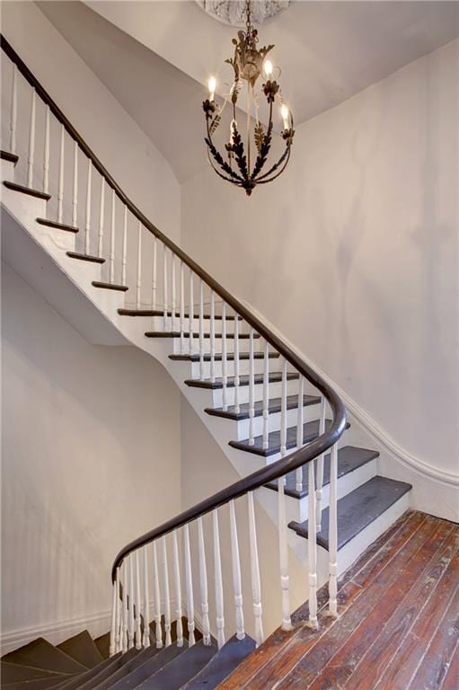 stairway featuring an inviting chandelier and hardwood / wood-style flooring