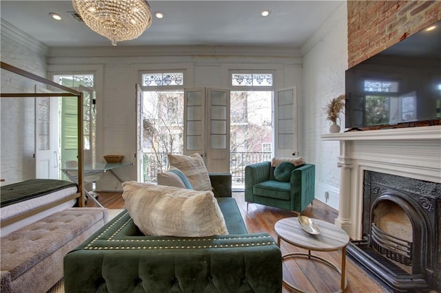 living room with an inviting chandelier, hardwood / wood-style flooring, and crown molding