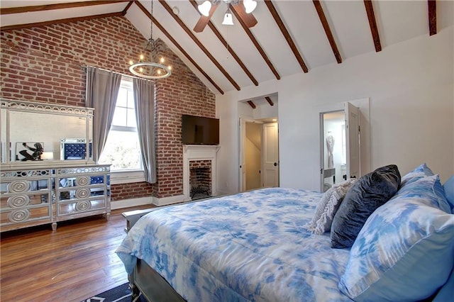 bedroom featuring dark hardwood / wood-style floors, beamed ceiling, ceiling fan with notable chandelier, brick wall, and high vaulted ceiling